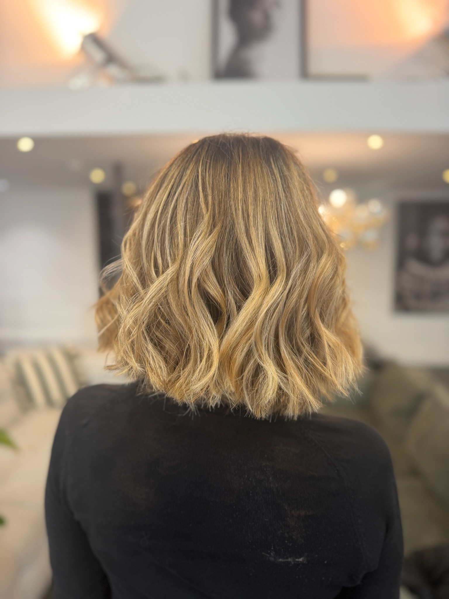 Vue de dos d'un carré mi-long ondulé, balayage blond doré et miel sur base châtain clair