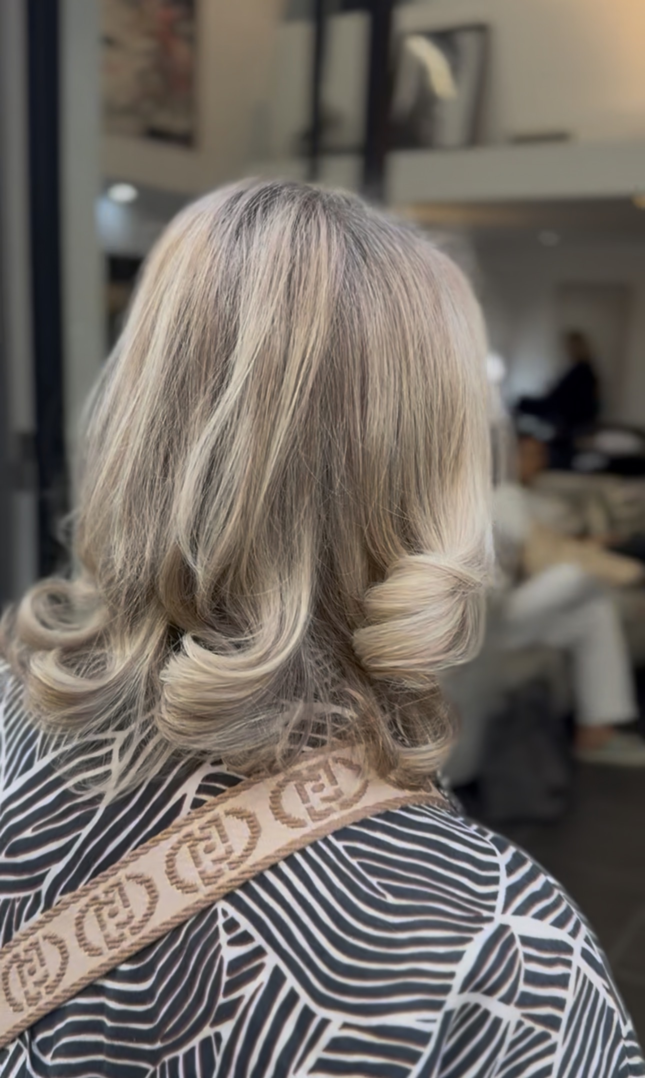 Blond platine cendré mi-long, pointes brushées en boucles souples