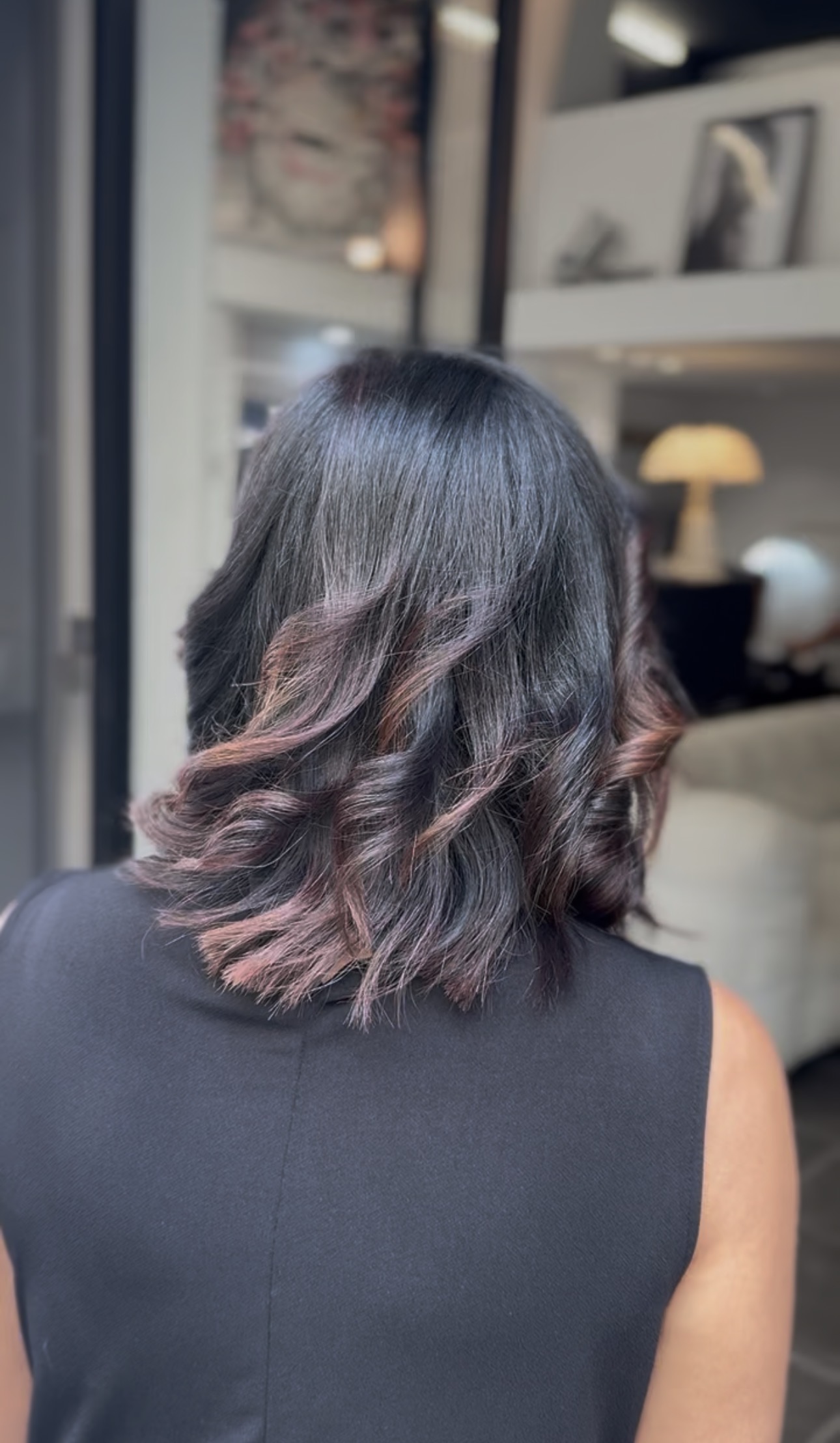 Vue de dos d'une coupe mi-longue ondulée sur base brun foncé, balayage cuivré aux reflets auburn sur les pointes