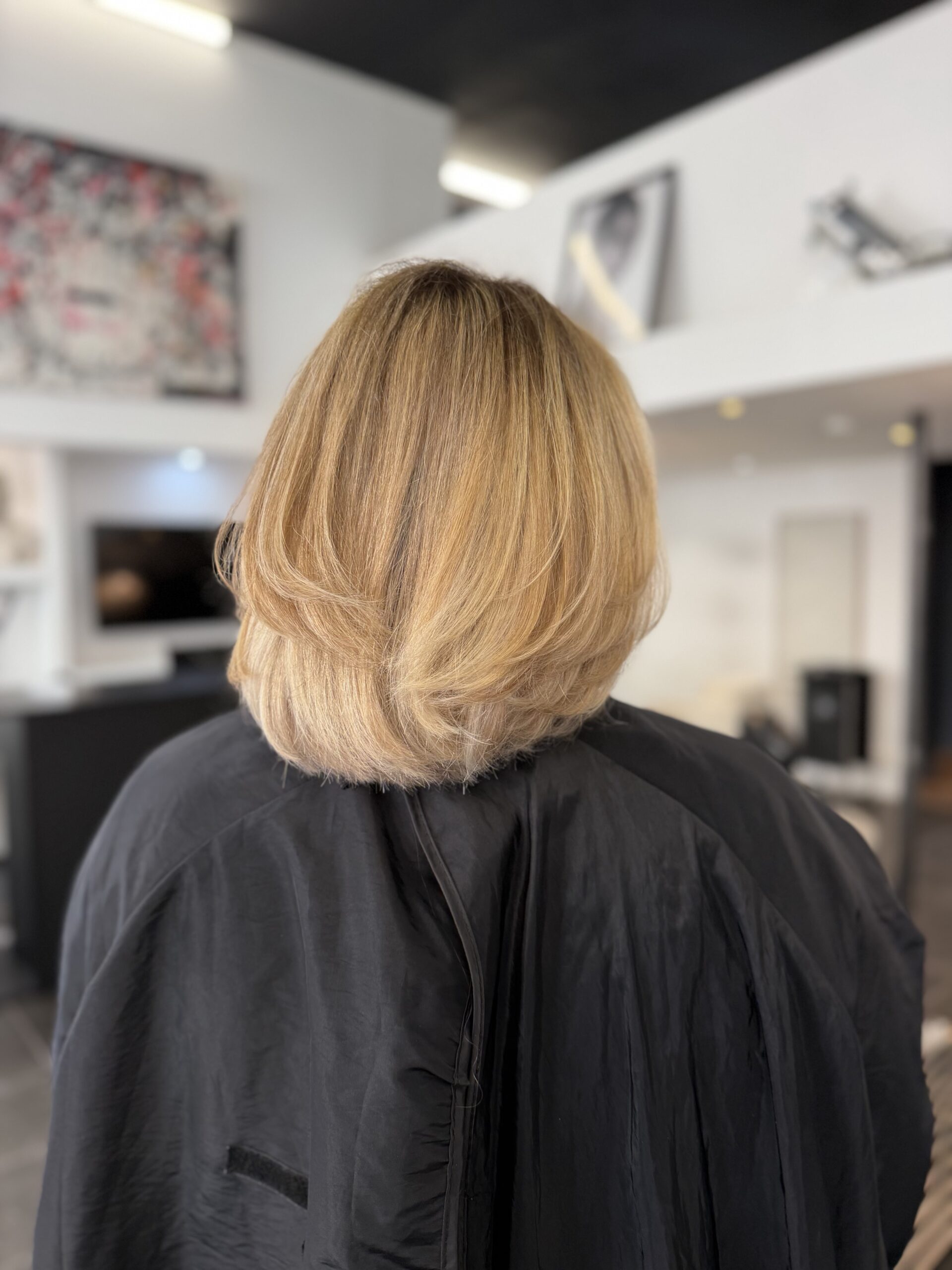 Vue de dos d'un carré mi-long dégradé et volumineux, balayage blond doré, miel et beige clair
