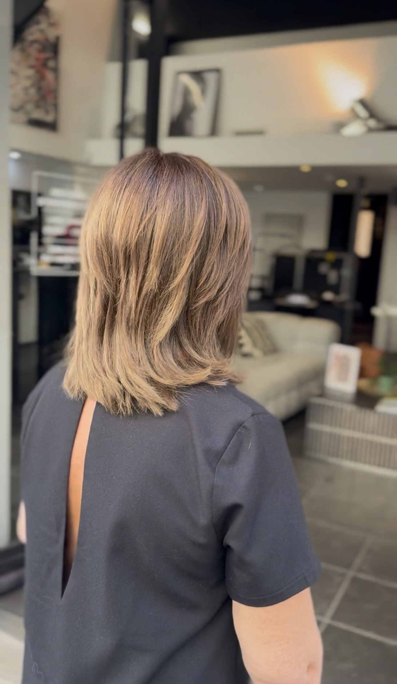 Coupe mi-longue dégradée aux pointes texturées, balayage blond miel lisse, vue de trois-quarts dos