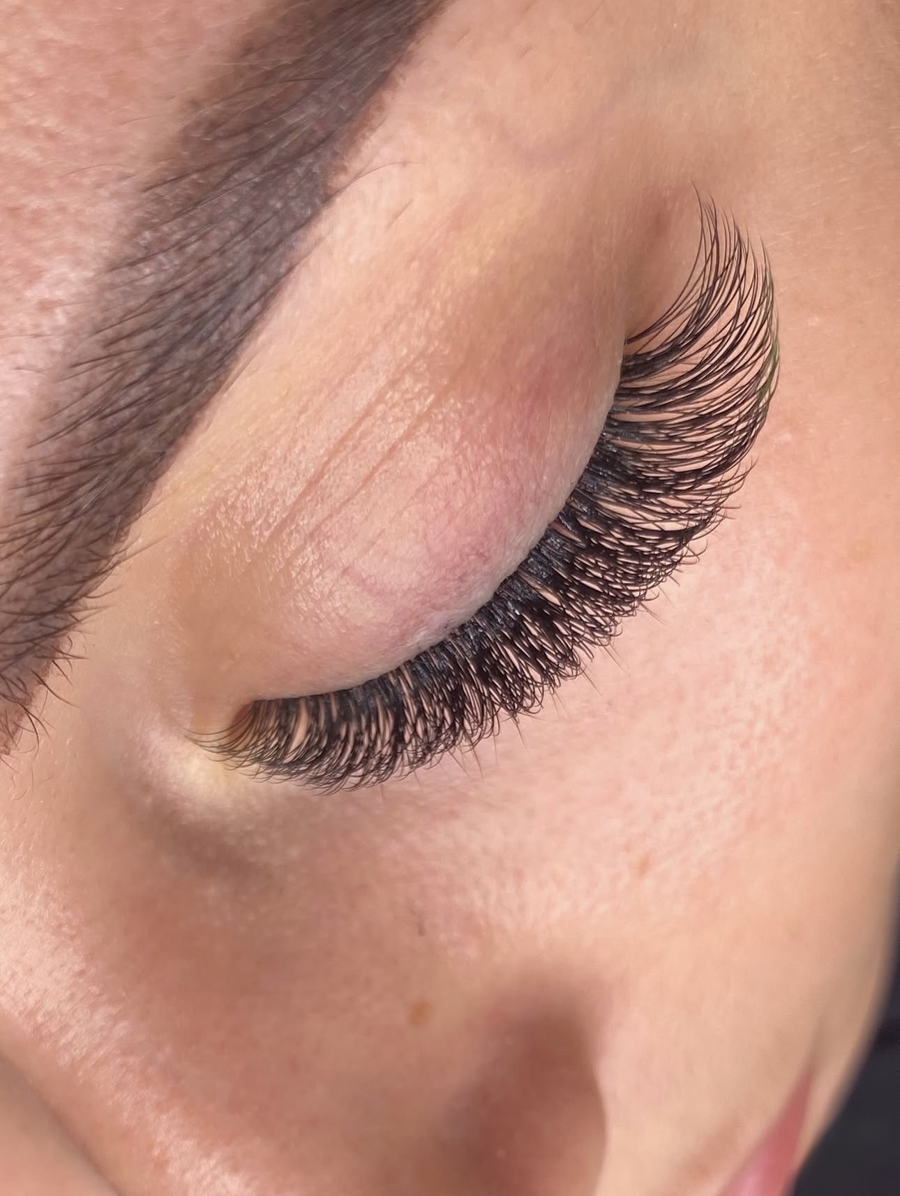Gros plan sur un œil fermé, extensions de cils volume russe dense et courbe effet œil-de-biche