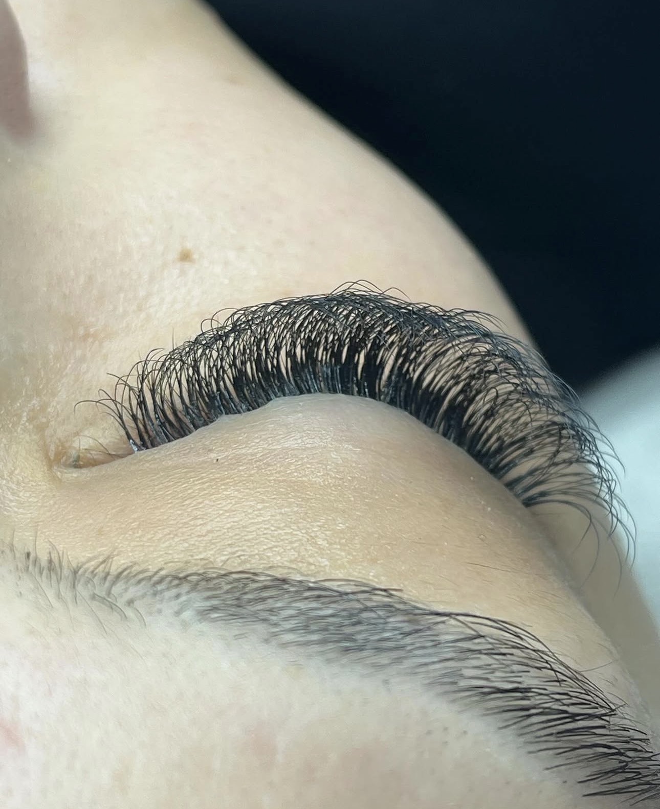 Gros plan sur un œil fermé, extensions de cils volume russe fournies et très courbées