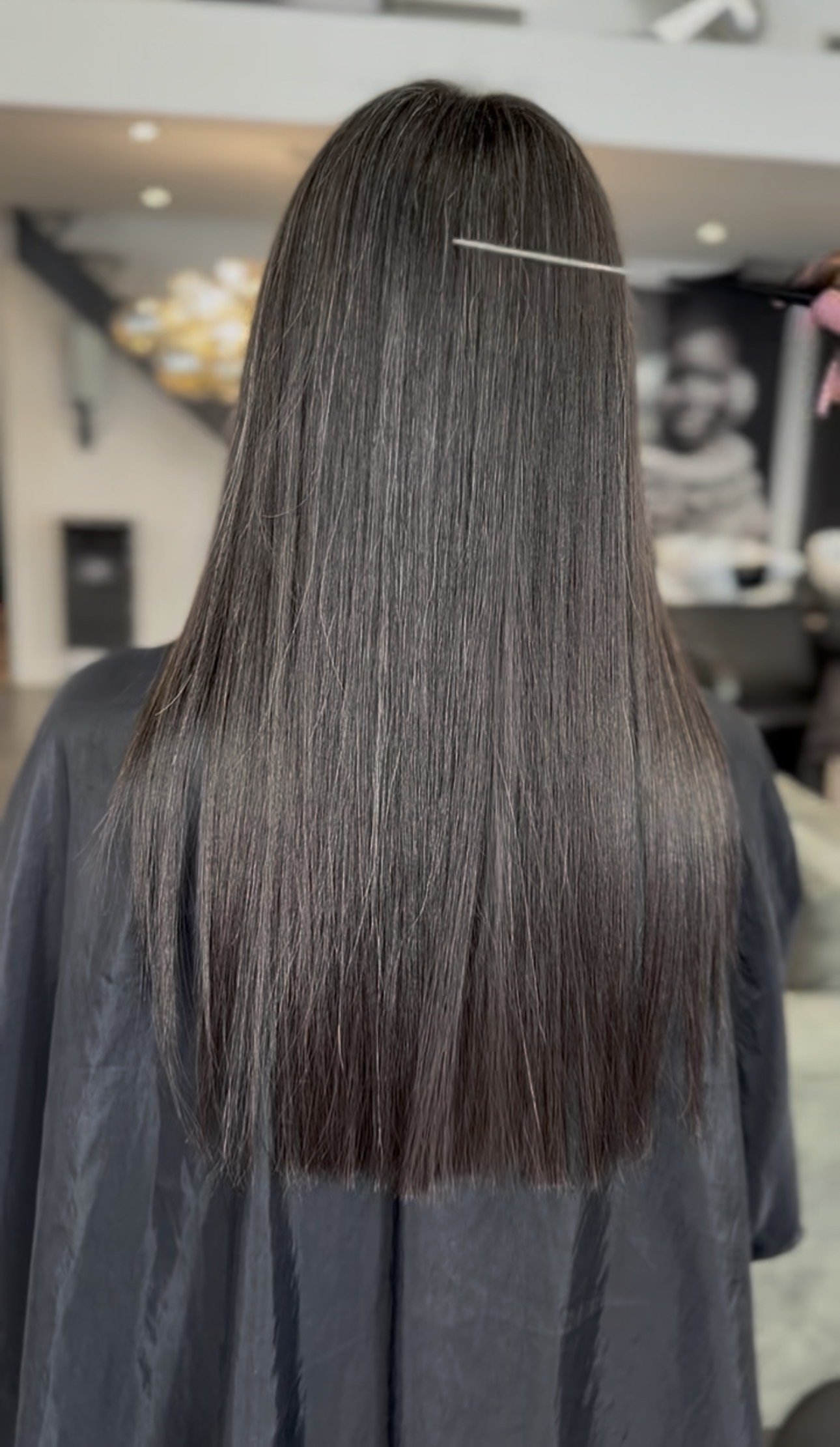 Cheveux longs lissés et lumineux vus de dos, résultat d'un lissage au salon