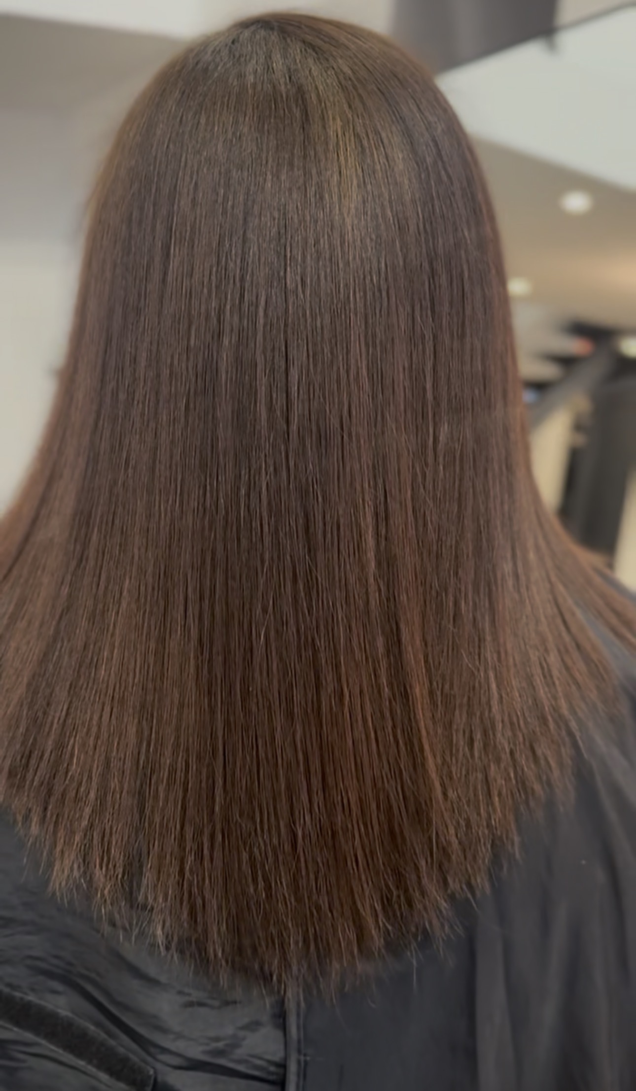 Cheveux lissés et brillants vus de dos, résultat d'un lissage au salon