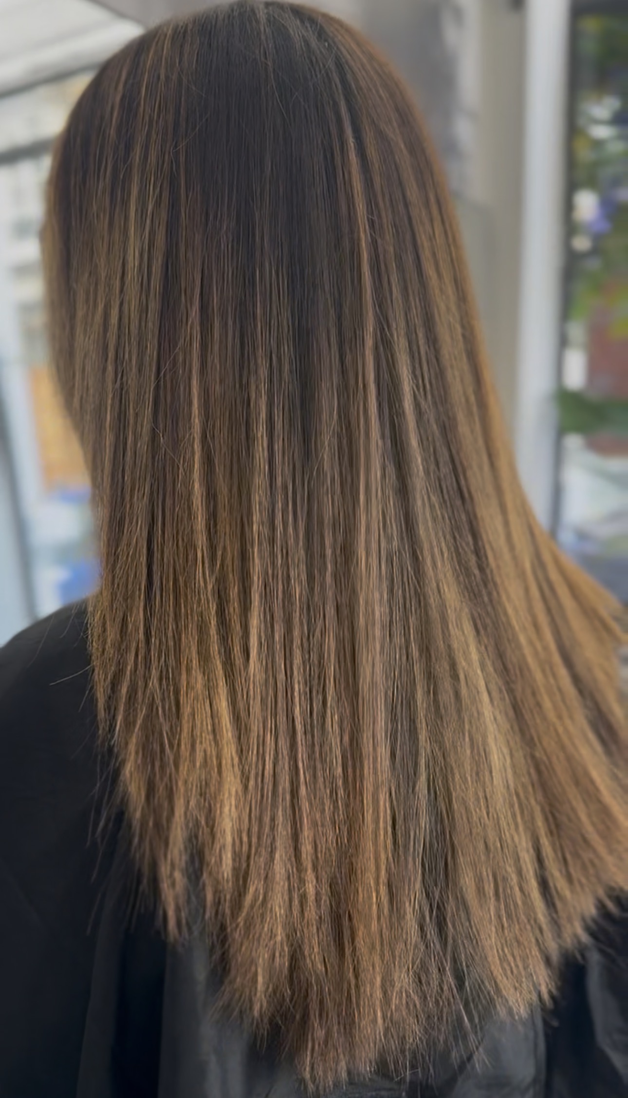 Cheveux lissés et fluides vus de dos, résultat d'un lissage au salon