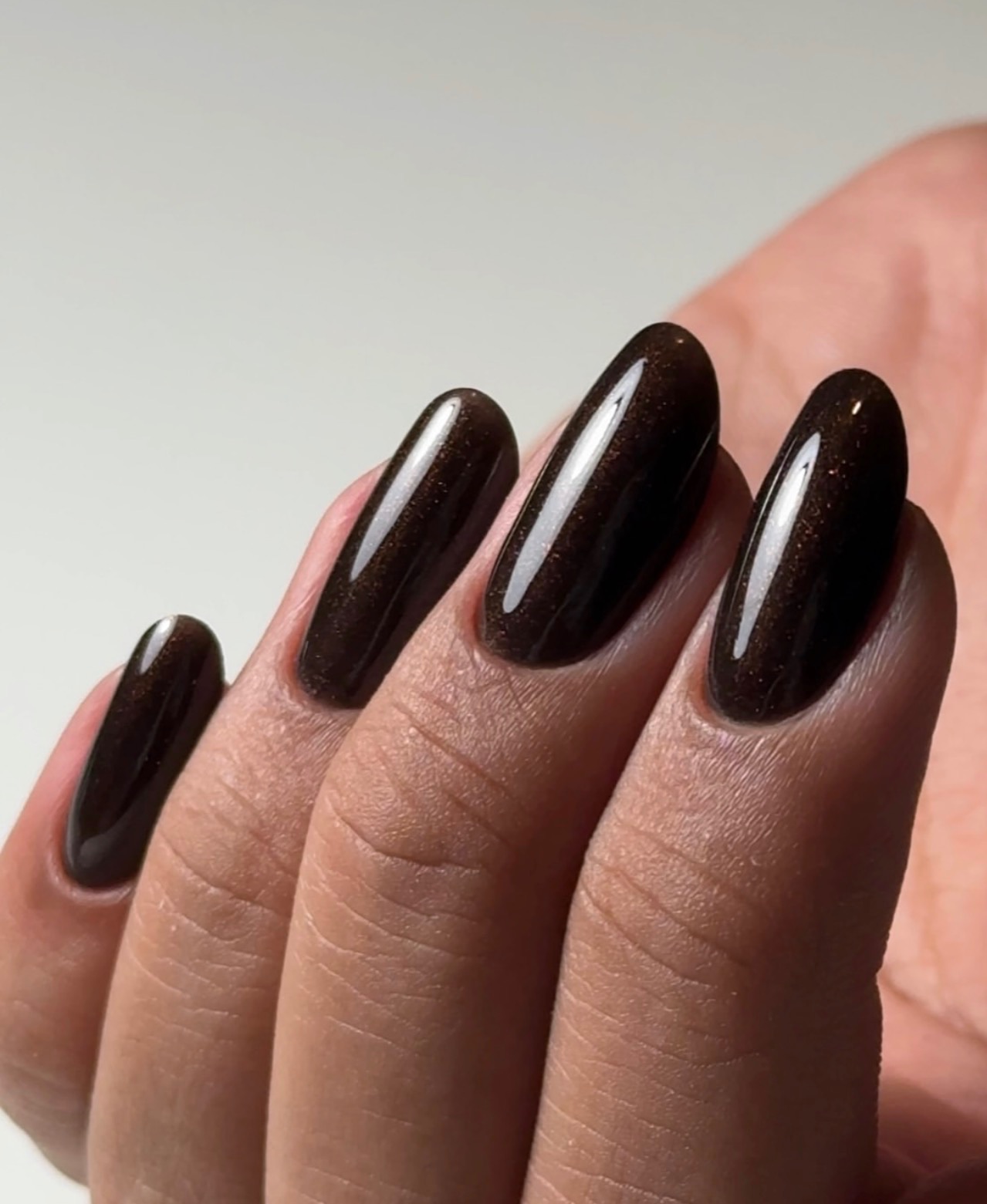 Ongles ovales vernis brun chocolat brillant avec fines paillettes cuivrées